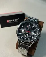 Curren 8363 plateado con esfera negra en un soporte, con su caja