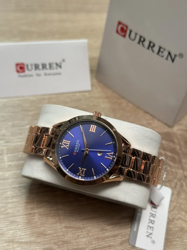 Curren 9007 oro rosa con esfera azul en su caja, con las etiquetas de la marca